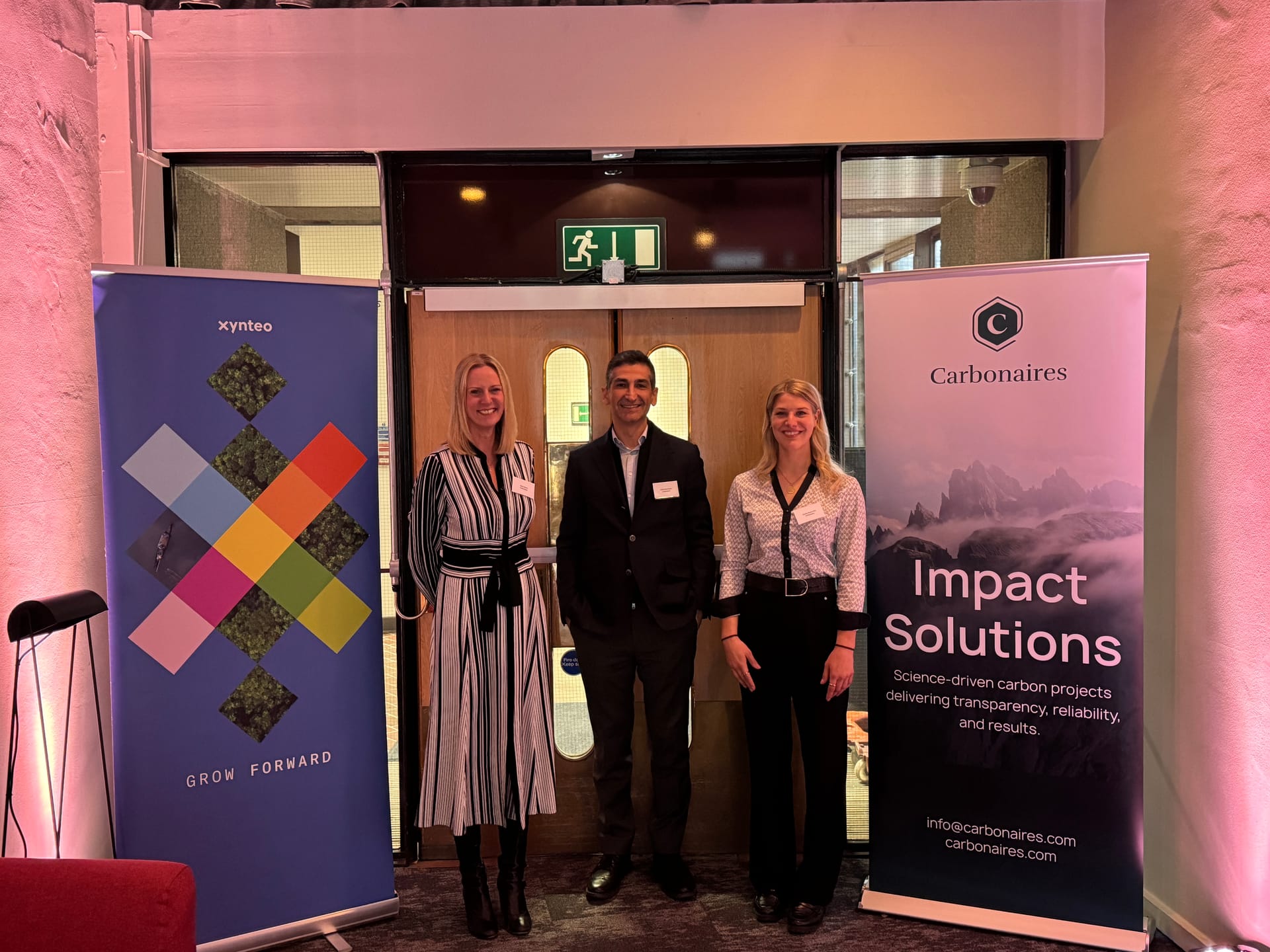 Representatives from Carbonaires and Xynteo standing between branded banners at the partnership event at the Barbican, London