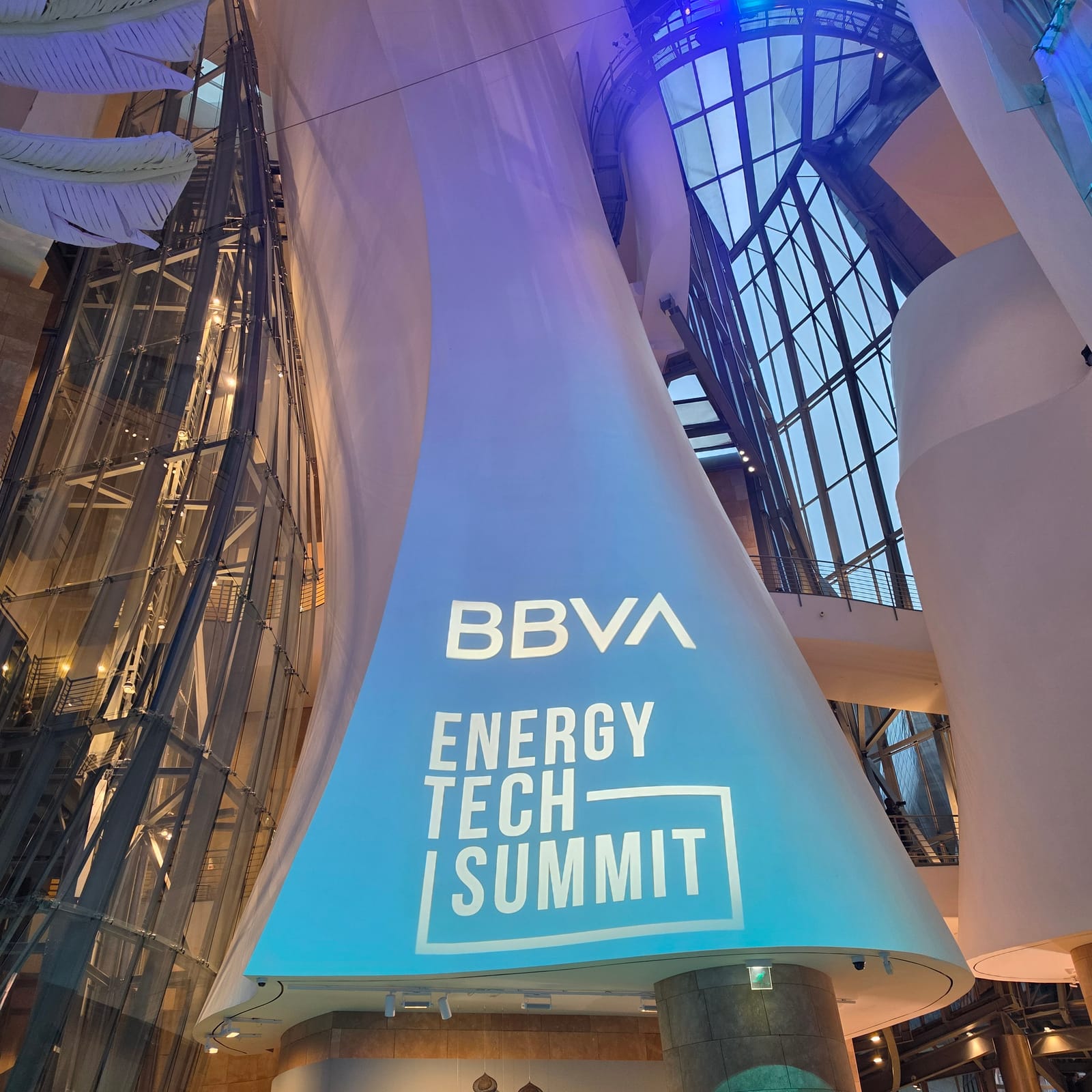 BBVA Energy Tech Summit banner suspended inside the Guggenheim Museum in Bilbao at night, framed by the museum’s curved titanium and glass architecture